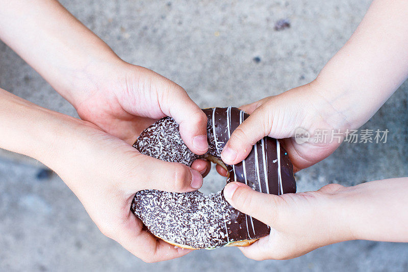 孩子们的手拿着一个巧克力甜甜圈