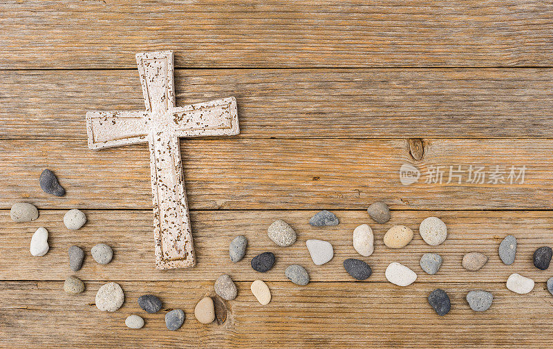 石头十字架与波浪卵石在木制的背景