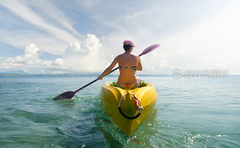 女人旅行者探索平静的热带海湾由皮艇