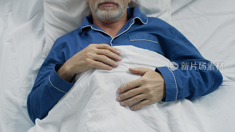 男性退休老人甜蜜地睡在床上，享受矫形床上的舒适