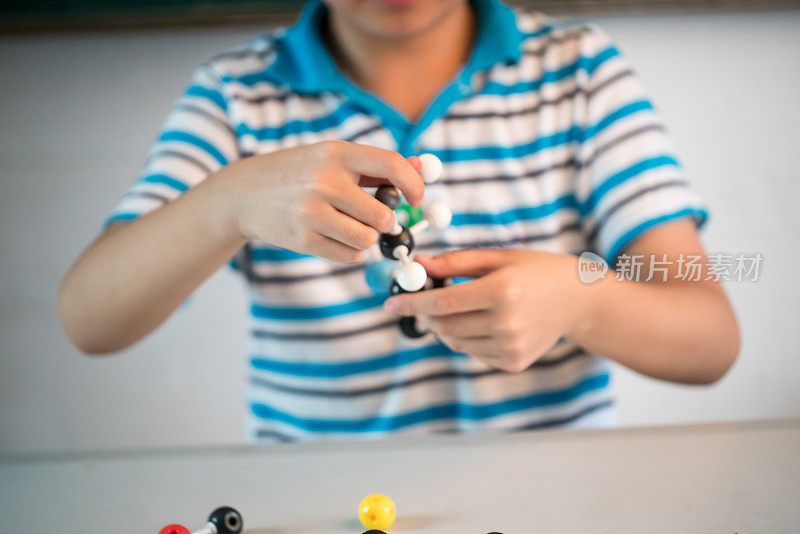 一个亚洲男孩在教室里玩球和棍子结构