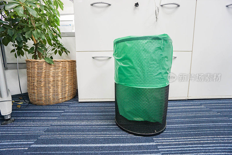 办公室内顶部装有绿色塑料袋的不锈钢垃圾桶