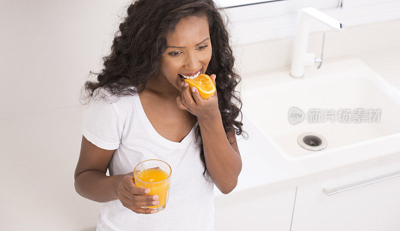 女人在品尝橙色的水果。