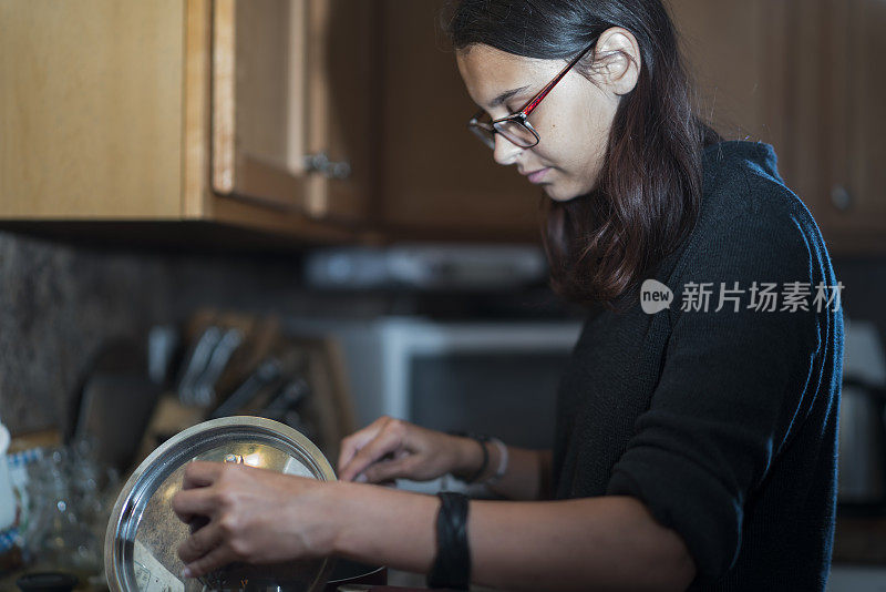 在宾夕法尼亚州波科诺的奥尔布莱特斯维尔，一个女孩在家里的厨房里准备食物