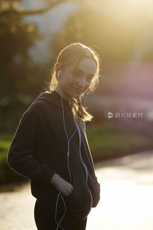 日落时分，一个十几岁的小女孩在街上听MP3