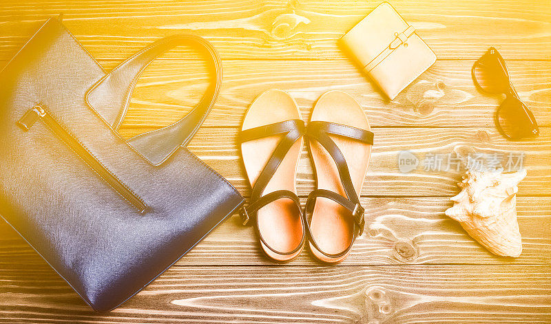 女人的包，凉鞋，钱包，眼镜，贝壳放在木桌上。女性的配件。旅游的概念。俯视图