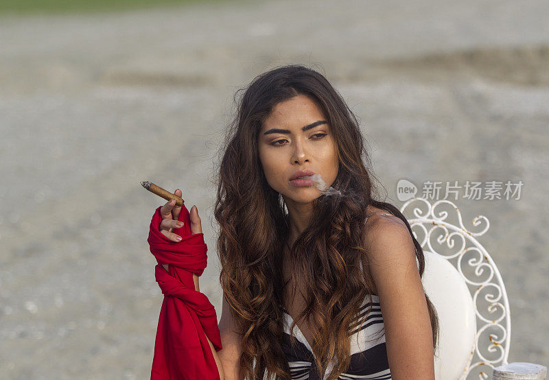 一名年轻的巴西妇女在土耳其伊斯坦布尔的西里夫里海滩上抽着雪茄