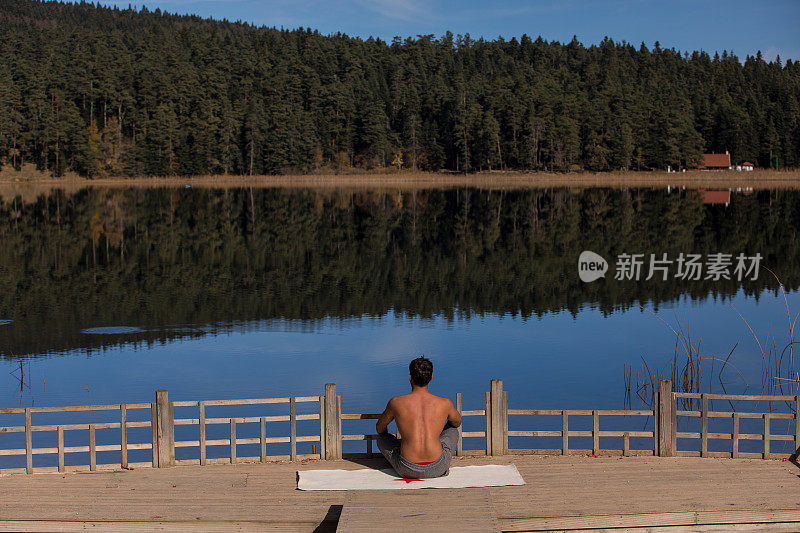 年轻人在大自然中做瑜伽锻炼，在湖边