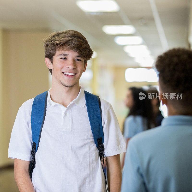 十几岁的男性在高中的走廊里微笑和交谈