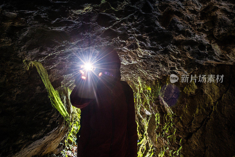 一个男人的剪影拿着一盏灯在山洞里