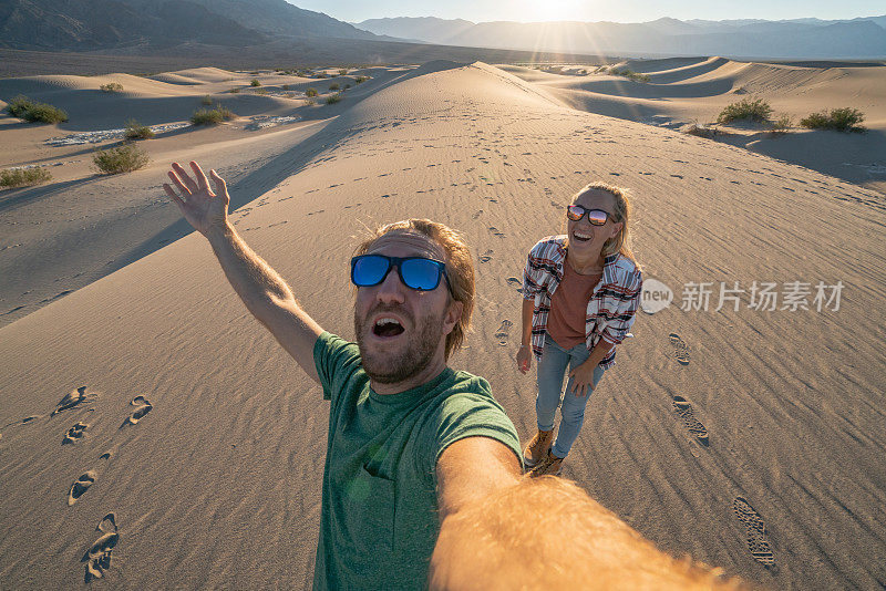 旅行的夫妇在日落时在沙丘上自拍