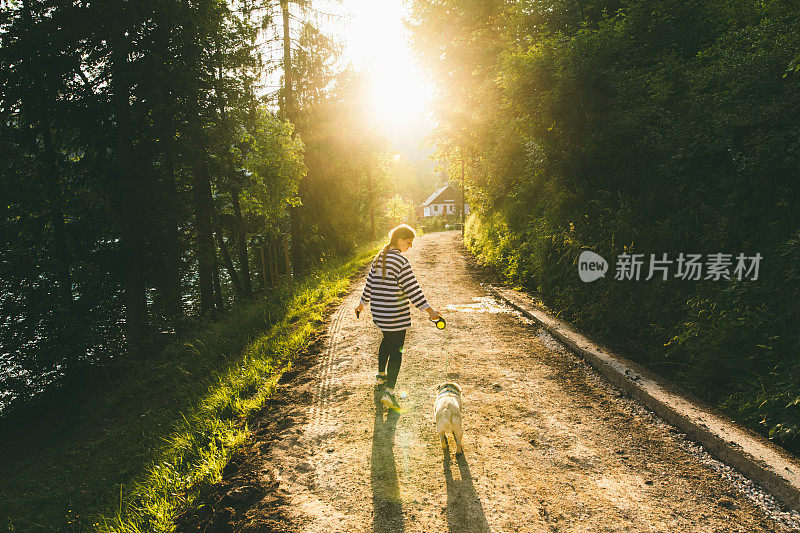 斯洛文尼亚，一名妇女在明媚的夕阳下遛狗