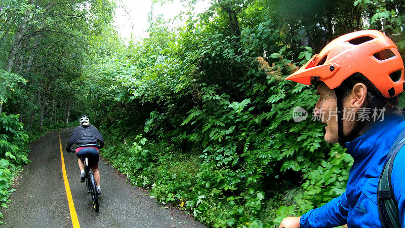 山地车跟随女人骑自行车通过热带雨林铺设小径