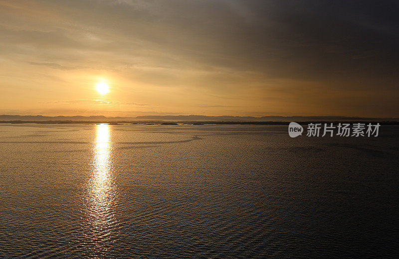 美丽宁静的挪威风景沐浴在一个平静的温暖发光的橙色黎明日出。山景逐渐退到背景中。有足够的空间来放置副本。