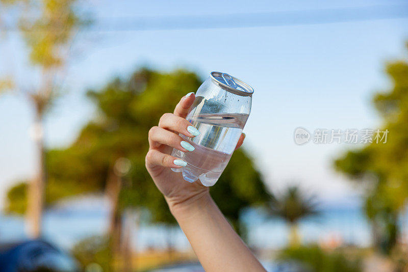 面目全非的女子拿着装着水的塑料罐，以大自然为背景