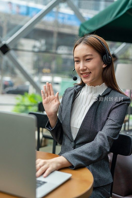 混合动力工作。年轻的亚洲女性成年女商人笔记本电脑和耳麦在咖啡馆工作。