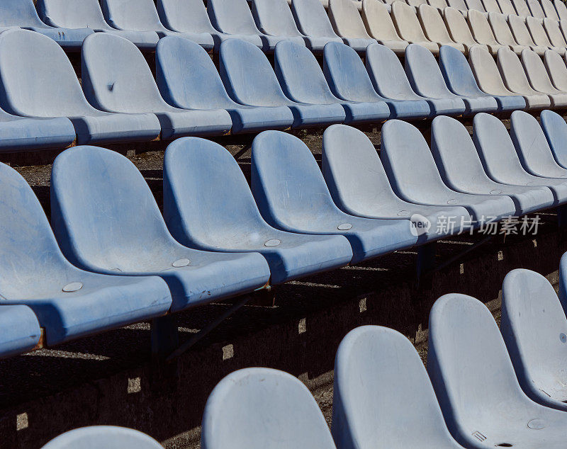成排的体育场看台座位。生锈的蓝白塑料体育场座椅。旧体育场里的蓝色椅子。