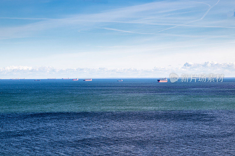 这是一张令人惊叹的无人机拍摄的海上照片，地平线上有多艘货船，展示了航运业的规模和美丽。水的艺术质感类似于噪音。