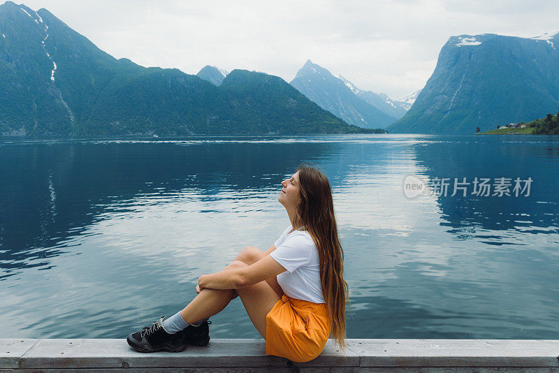 一个快乐的女人凝视着挪威峡湾的景色