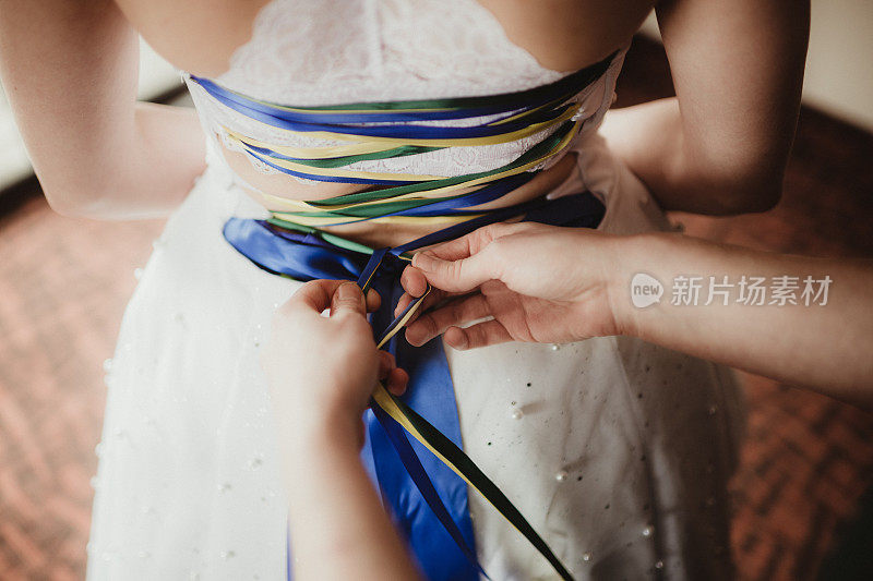 新娘用缎带系好结婚礼服的后襟