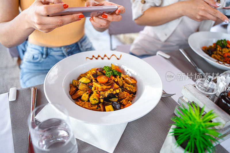 女游客在餐馆里拍摄传统美食