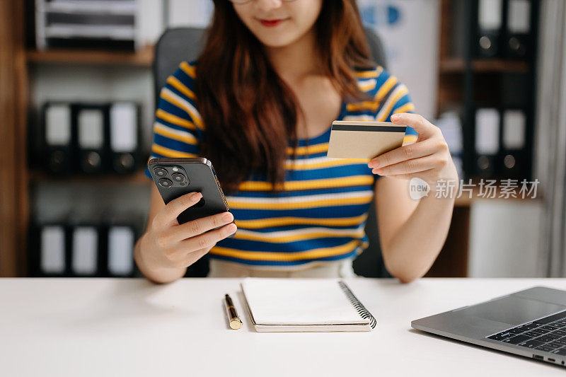 亚洲女性使用智能手机进行移动支付、网上购物、全渠道、坐桌、虚拟图标图形界面屏幕