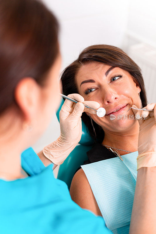 在牙科诊所给这位女士装牙套。牙医在牙科诊所检查戴牙套的女病人。一个年轻迷人的女孩戴着牙套的特写