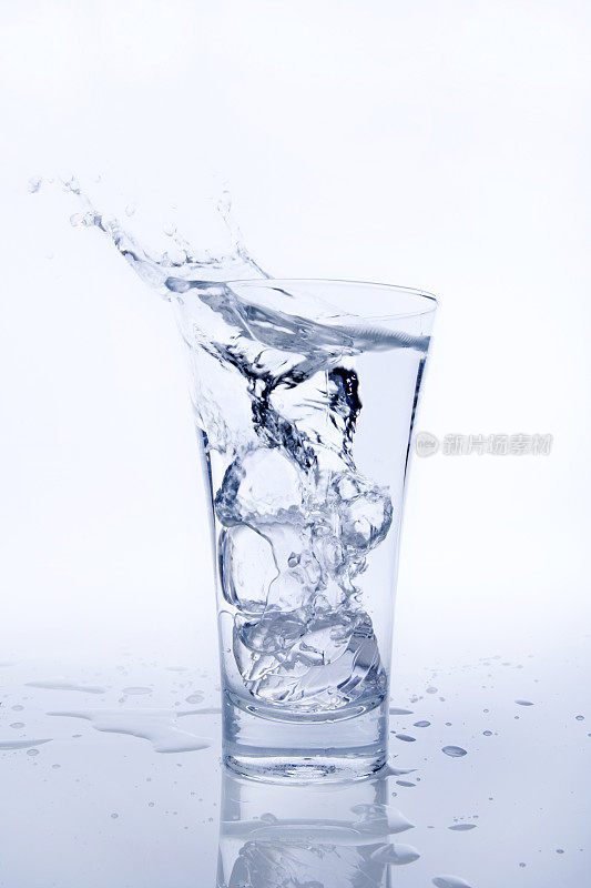 玻璃杯中的水和下落的冰块