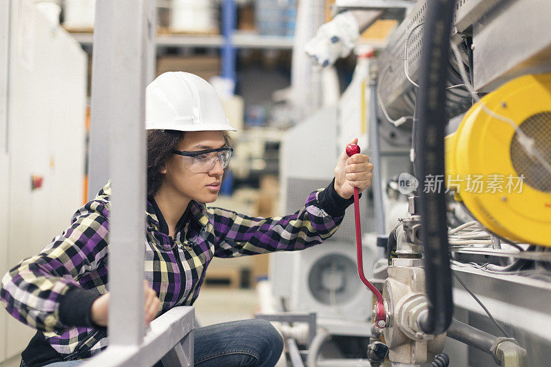 漂亮的女工人在工厂里操作机器