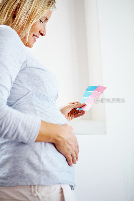 成熟的孕妇选择一种颜色来粉刷墙壁