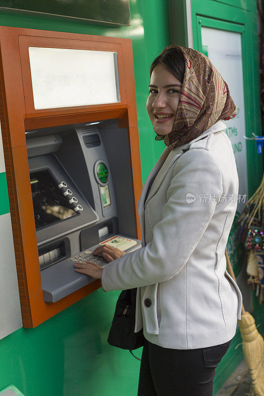 独立的年轻穆斯林妇女使用自动取款机