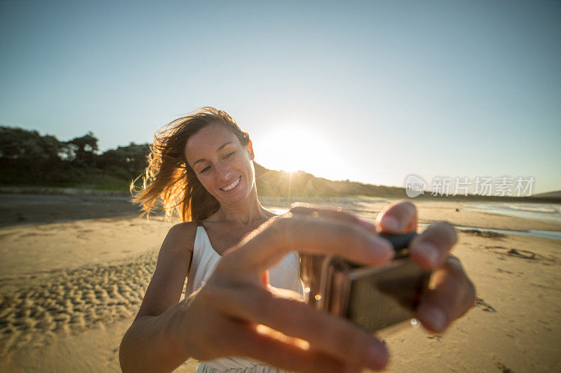 一名年轻女子在海滩上用可穿戴相机自拍