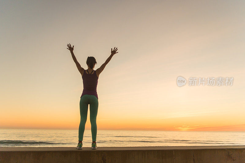 年轻女子在夕阳下奔跑的剪影