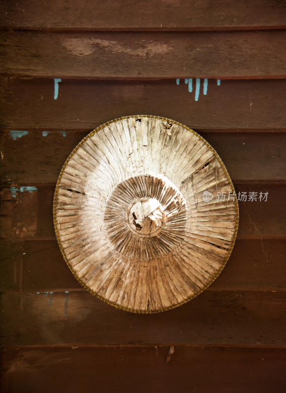 木制墙上挂着一顶古老的亚洲锥形帽子