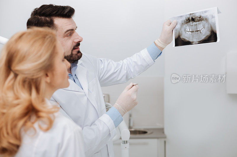 聪明的牙医正在给他的同事看扫描图
