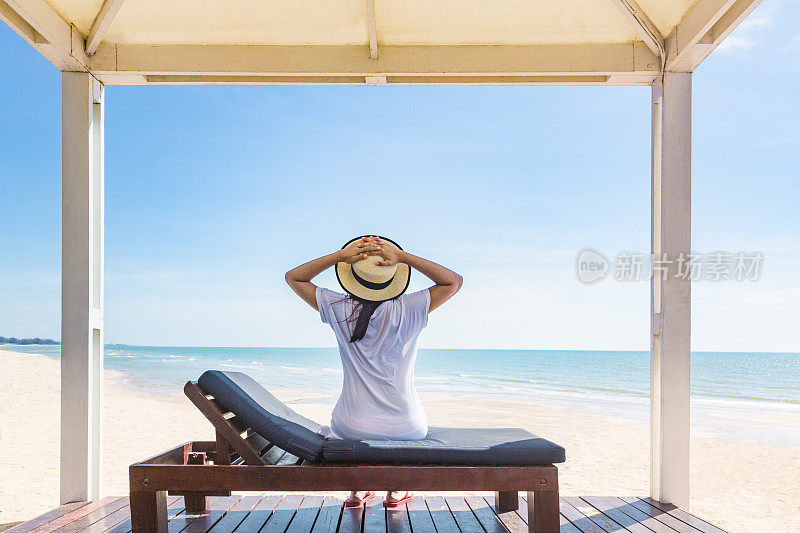 女人放松在海滩躺椅或阳光甲板上的海滩上的海景，度假的概念海滩和海在夏季假期