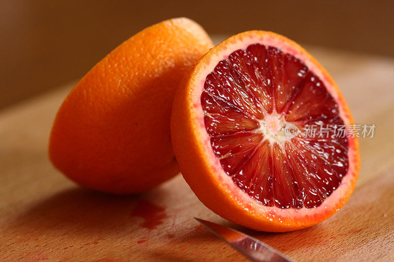 在木桌上用刀片切成两半的血橙