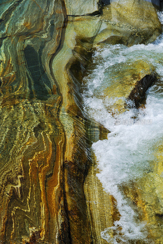 彩色岩石在清澈的水流下的特写。