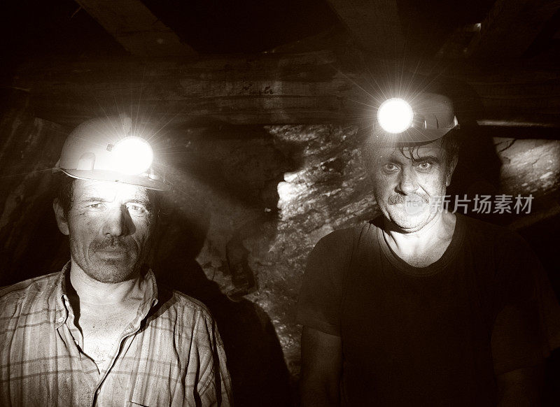 两名矿工在矿井里摆姿势的照片