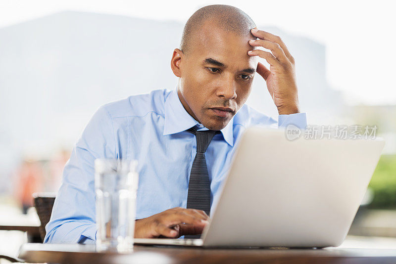 非裔美国商人在户外使用笔记本电脑。