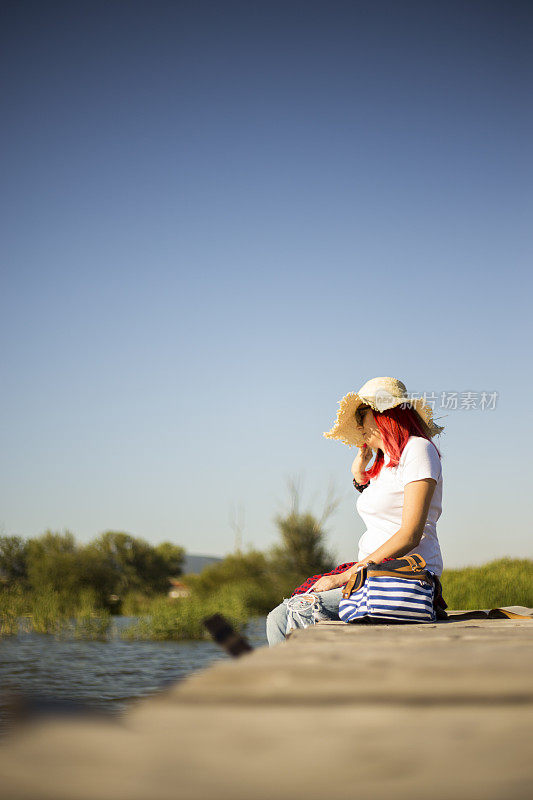 年轻美丽的女孩坐在码头上