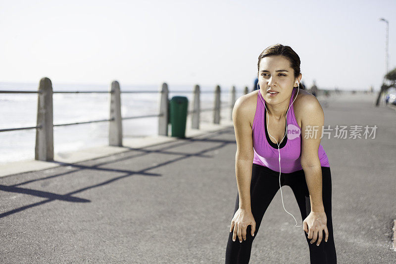 美丽的女人跑步后在海滩边休息