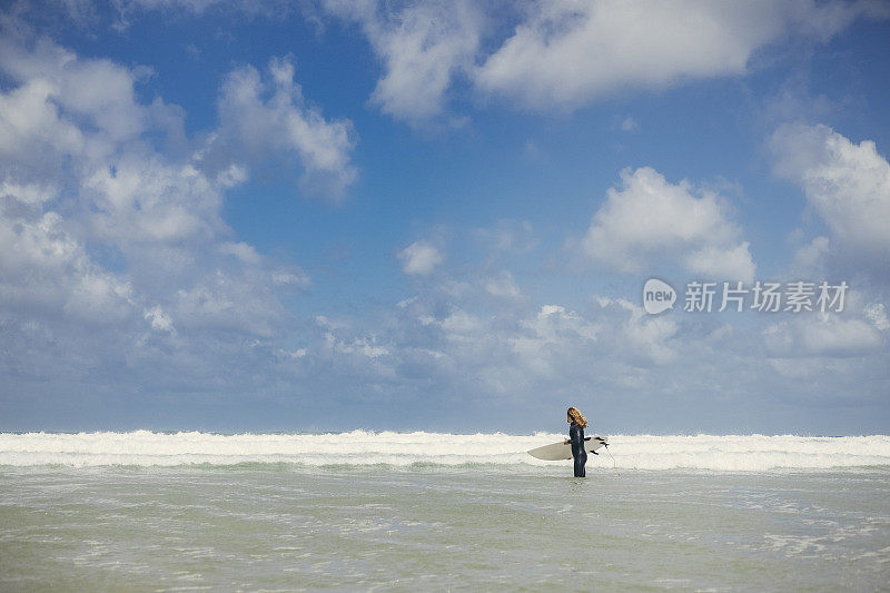 男冲浪者站在海里与冲浪板，晴朗的六月天，纽基。