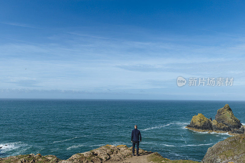 一名男子站在那里眺望南康沃尔海岸的景色。