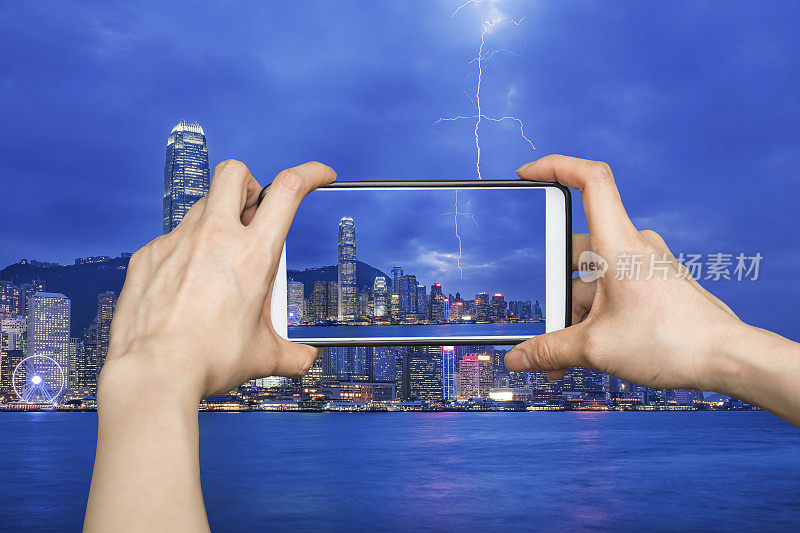 一个女孩用手机拍下了香港雷雨夜景，香港城市。