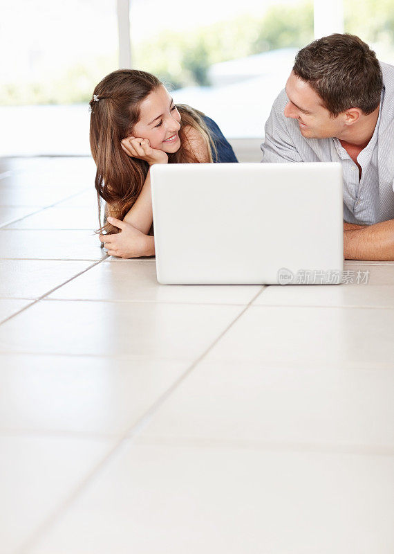 女儿和父亲一边看着对方一边拿着笔记本电脑