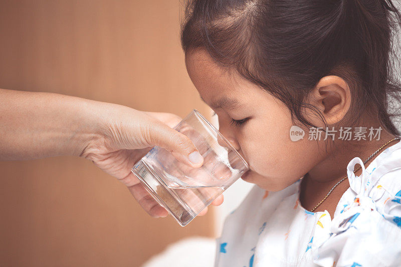 母亲亲手给住院的生病的小女孩送水
