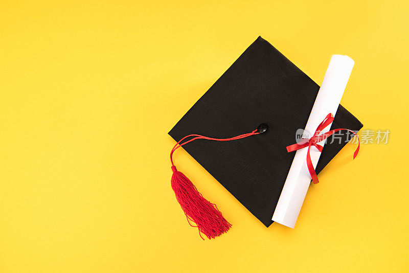 俯视毕业学位帽和毕业证书上的黄色背景，教育理念