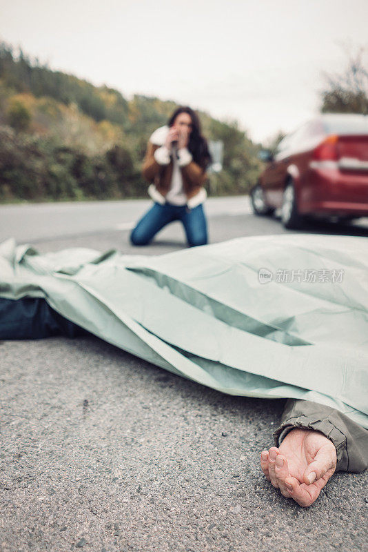 吓坏了的女人在打电话，而死者躺在前景。