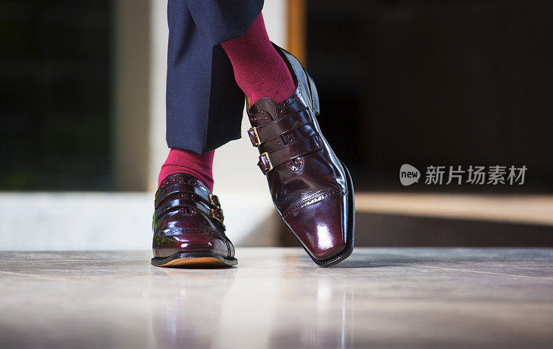 时尚的男人站在皮带扣的鞋子和红袜子
